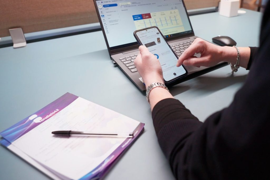 Persona che utilizza smartphone e computer laptop per controllare i dati delle campagne Google ADS